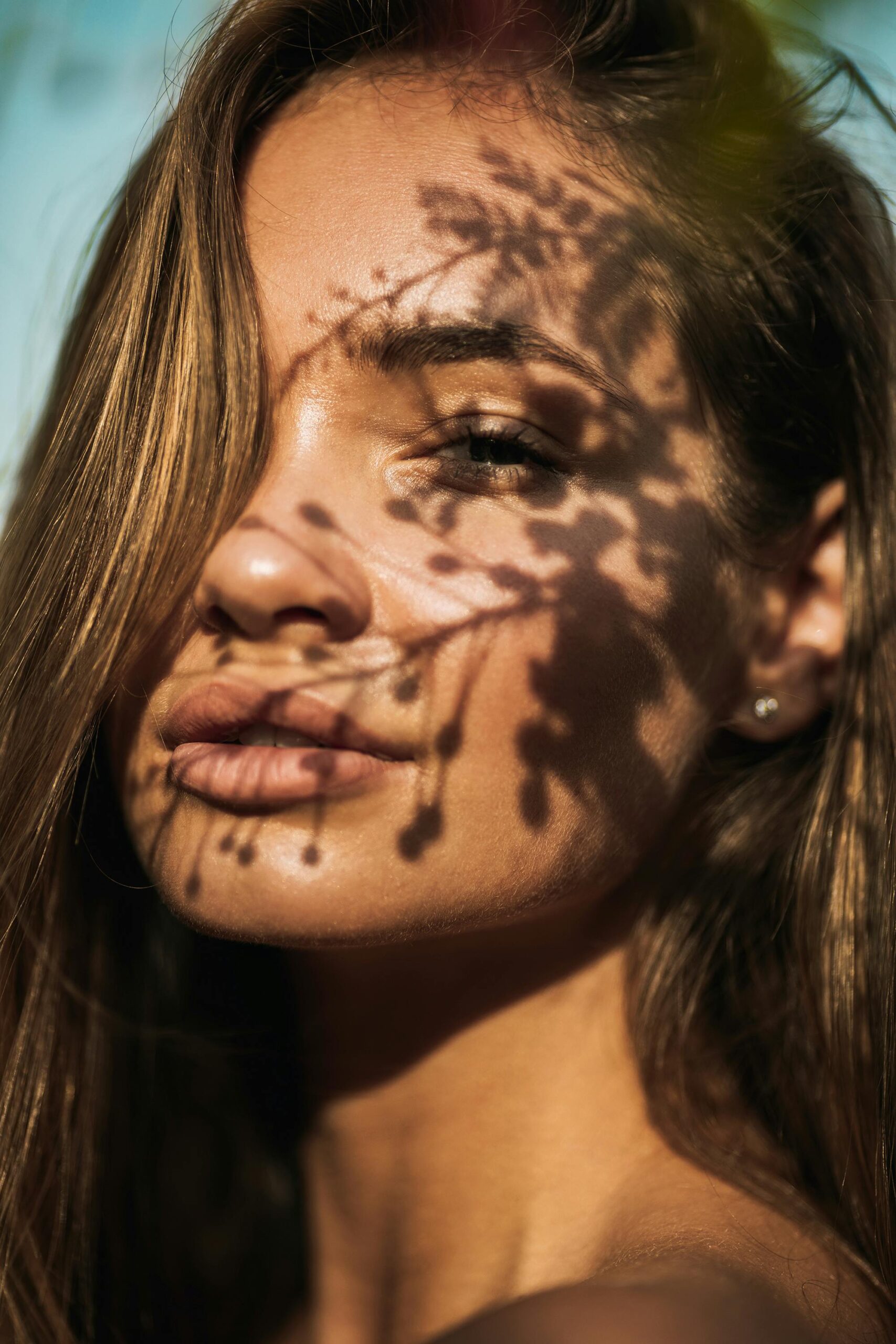 Close-up portrait of a woman with floral shadows on her face, captured in Dubai.